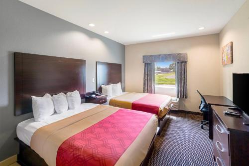 a hotel room with two beds and a television at Econo Lodge Baton Rouge University Area in Baton Rouge