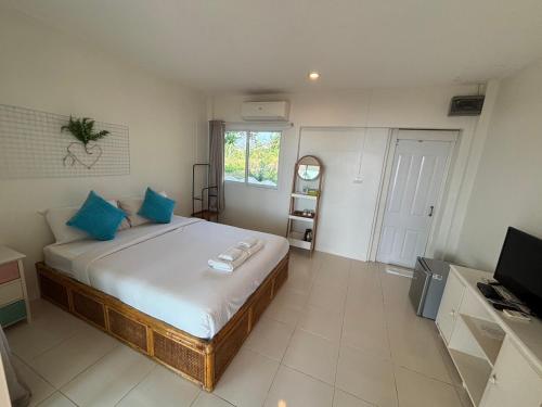 a bedroom with a bed with blue pillows and a television at Issara Beach Resort in Sichon