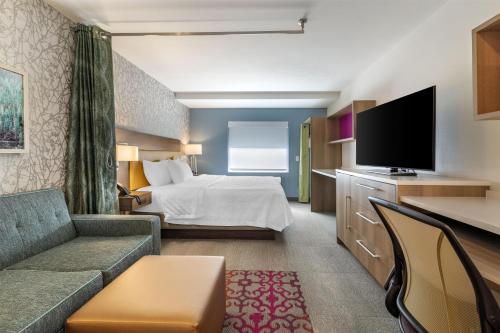 a hotel room with a bed and a flat screen tv at Home2 Suites by Hilton Bangor in Bangor