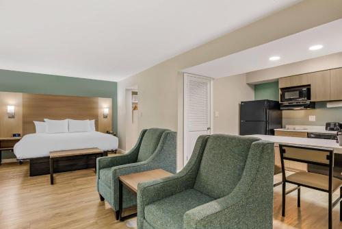 a hotel room with a bed and two chairs at MainStay Suites Springfield South - Battlefield Rd in Springfield