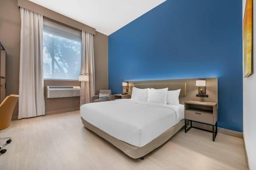a bedroom with a large white bed and a blue wall at Comfort Inn & Suites Orlando Sanford Airport in Sanford