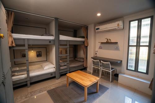 a room with bunk beds with a table and a desk at Bud Brew Beyond Dispensary and Hotel in Bangkok
