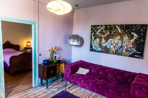 a living room with a purple couch and a painting at petite maison artistique in Saint-Plantaire