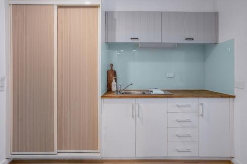 a kitchen with white cabinets and a sink at Bay View - Palm Springs in Lorne
