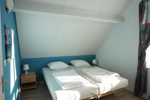 a small room with a bed with two white pillows at Kustverhuur , Park Scheldeveste, Zwin 143 in Breskens