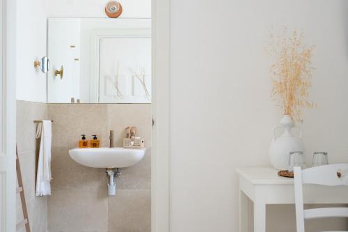 a white bathroom with a sink and a mirror at Oltre gli Ulivi in Ostuni