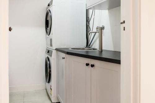 a kitchen with a sink and a washer and dryer at Maison del Mar in Hobart
