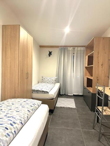 a bedroom with two beds and a cabinet and a table at Gemütliches Doppelzimmer Gemeinschaftsbad in Dingolfing