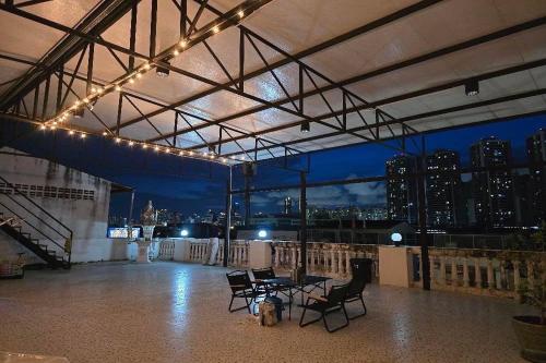 a rooftop patio with chairs and a table and lights at Sukhum Huai Khwang Guest House in Bangkok