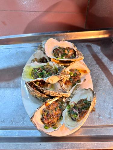 four oysters on a plate on a glass table at Hương Dịu Hotel đảo Quan Lạn in Quan Lạn