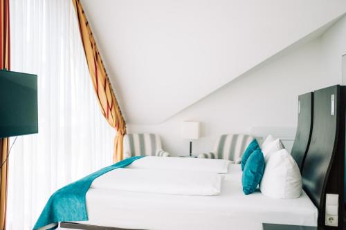 a bedroom with a white bed with blue pillows at DämeritzSeehotel in Berlin
