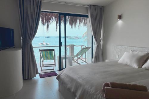 a bedroom with a bed and a view of the ocean at Anchovy Beachfront Villas in Phú Quốc