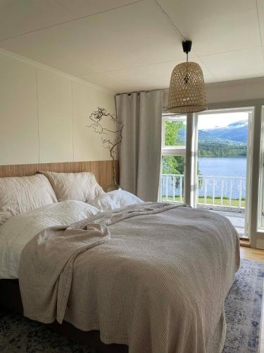 a bedroom with a bed and a large window at Lake House in Vossevangen