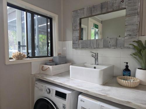 a bathroom with a sink and a washing machine at CHILL-OUT BEACH HOUSE - One Mile Beach in Forster