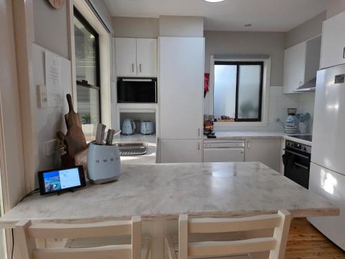 a kitchen with a table with a laptop on it at CHILL-OUT BEACH HOUSE - One Mile Beach in Forster