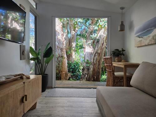 a living room with a sliding glass door to a tree at CHILL-OUT BEACH HOUSE - One Mile Beach in Forster