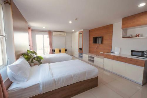 a bedroom with a large white bed and a kitchen at The Seasons in Pathum Thani