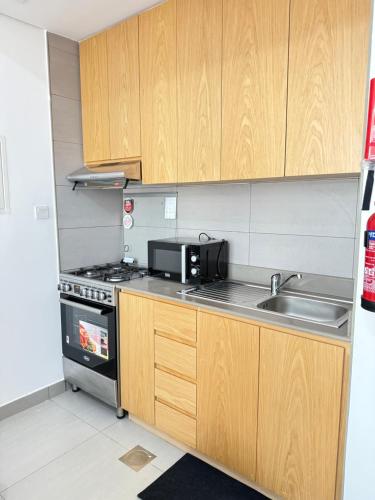 a small kitchen with a sink and a microwave at Modern studio with pool and fiber connection in Sharjah