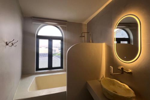 a bathroom with a tub and a sink and a mirror at Anchovy Beachfront Villas in Phú Quốc