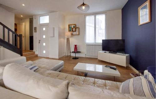 a living room with a white couch and a tv at Charmante Maison Proche Mer in Royan