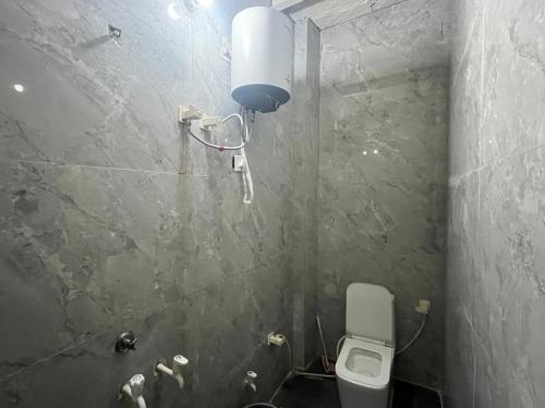 a bathroom with a toilet and a light on the wall at Hotel Moonlight in Chhatikara