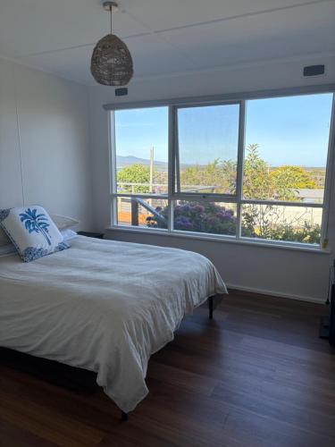 a bedroom with a bed and a large window at Serenity House in Mallacoota