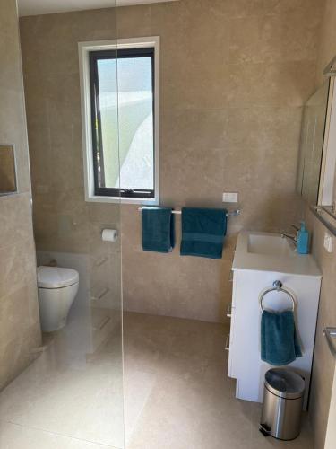 a bathroom with a shower and a sink and a toilet at Serenity House in Mallacoota