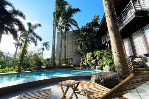 ein Schwimmbecken mit zwei Stühlen und ein Gebäude in der Unterkunft Stardust Beach Hotel Matabungkay Batangas in Lian