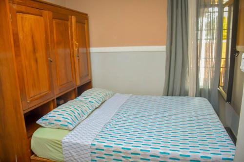 a bedroom with a bed and a wooden cabinet at Appart Naxel in Kinshasa