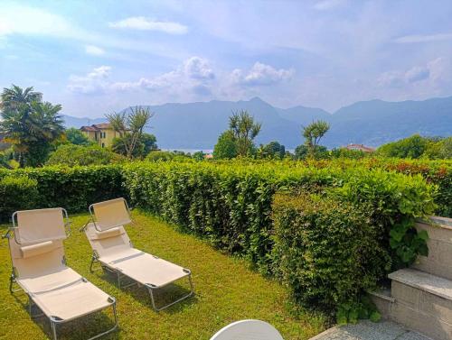 two chairs sitting on the grass next to a hedge at Residenz Lagobello in Germignaga