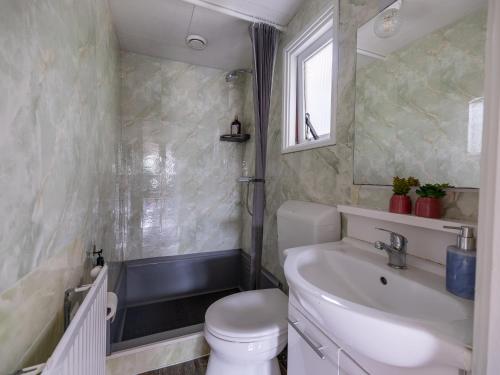 a bathroom with a sink and a toilet and a mirror at Ermrest Cottage in Erm