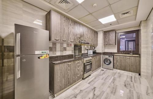 a kitchen with wooden cabinets and a stainless steel refrigerator at Grand Stay Holiday Homes Al Jaddaf in Dubai