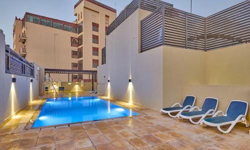 a swimming pool in the middle of a building with chairs at Grand Stay Holiday Homes Al Jaddaf in Dubai