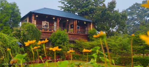 a wooden house with a balcony in a garden at Jewel Stay in Tāla