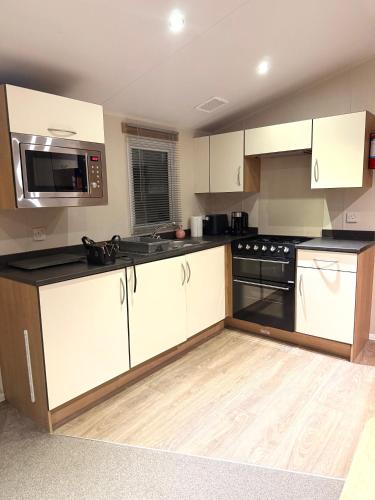 a kitchen with white cabinets and black appliances at Cozy Family Caravan at Haven Kent Coast in Allhallows