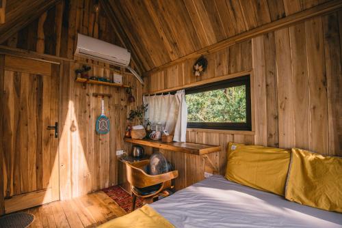 a bedroom with a bed in a wooden cabin at U Lesa Retreat - Nhà Bên Rừng in Sóc Sơn