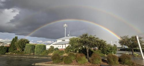 a rainbow in the sky over a building at Ranfurly Hostel with Sauna in Ranfurly