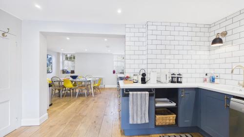 a kitchen with blue cabinets and a dining room at Arden Villa, sleeps 8, moments from the golden sandy beach of Ryde in Ryde