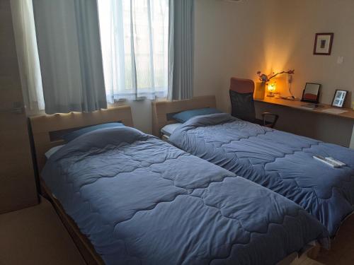 a bedroom with two beds and a desk and window at ル カフェ プランタニエ in Yokote