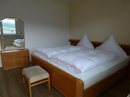 a bedroom with a bed with white sheets and a stool at Ferienwohnung Hermann Miß in Bad Berleburg