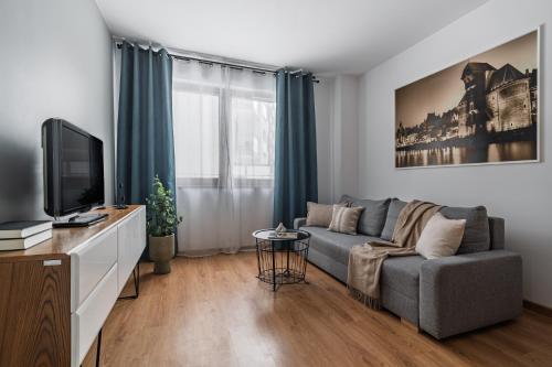 a living room with a couch and a tv at Flatbook - City Center SPA Apartments A,B,C in Gdańsk