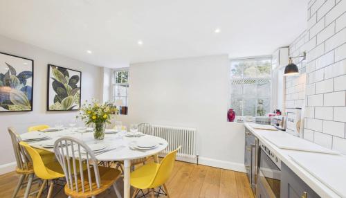 a white kitchen with a table and yellow chairs at Arden Villa, sleeps 8, moments from the golden sandy beach of Ryde in Ryde