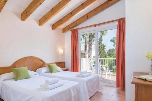 two beds in a room with a balcony at Villas Serena in Cala Blanca