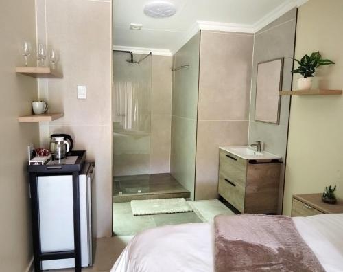 a bedroom with a shower and a sink and a bed at Homely Haven Guest House in Roodepoort