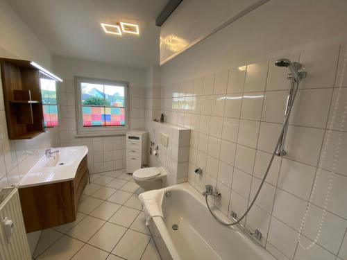 a bathroom with a tub and a toilet and a sink at Gästehaus Siebert in Lobbe