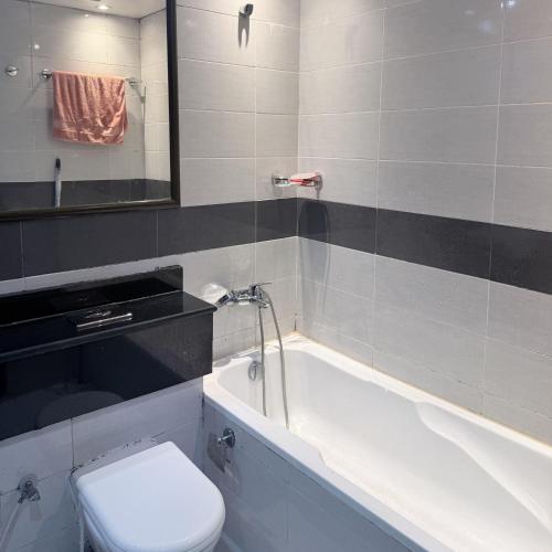 a bathroom with a tub and a toilet and a sink at Burdubai Vacation Homes in Dubai