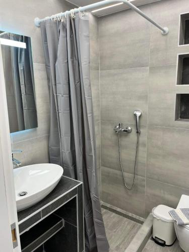 a bathroom with a shower curtain and a sink at Kyano Studios-Sotiria studios in Limenaria