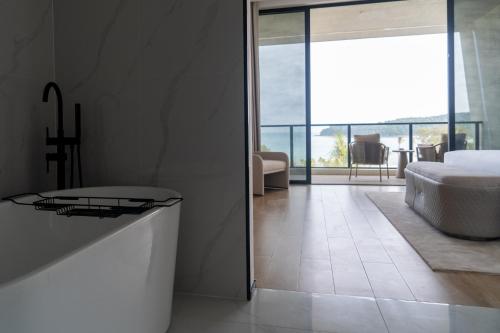 a white bathroom with a tub and a bedroom at Xanadu International Resort in Koh Rong Sanloem