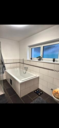 a white bathroom with a tub and two windows at Gästezimmer Mürztal in Langenwang Schwöbing