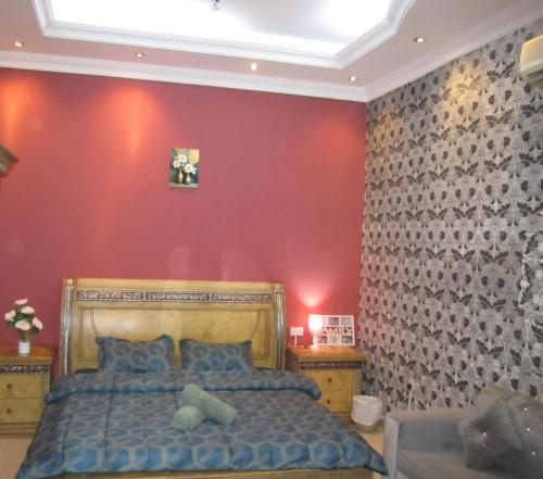 a bedroom with a bed and a red wall at العين الهيلي مصباح بيت14 in Al Ain